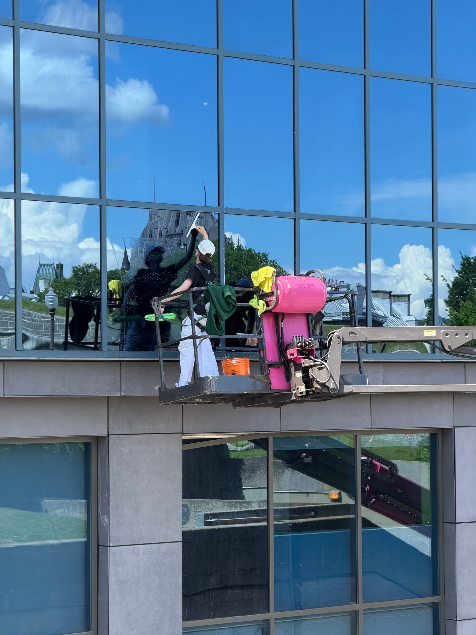 Technicien Bouchneau lavant les vitres d’un bâtiment commercial depuis une nacelle