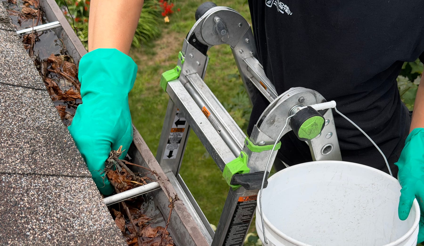Technicien Bouchneau retirant manuellement les feuilles et les débris d’une gouttière