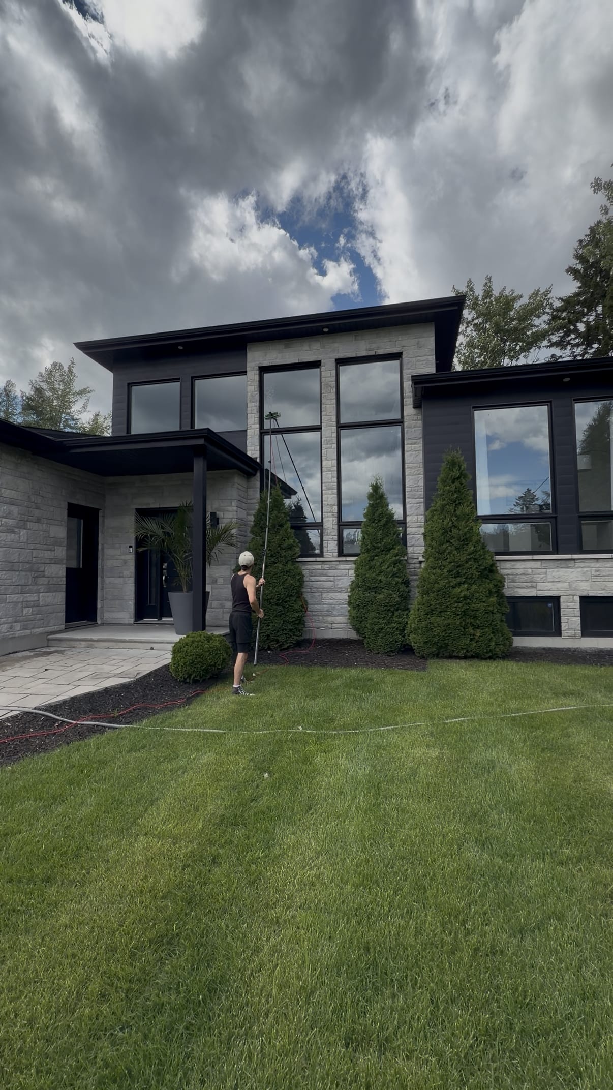 Technicien Bouchneau lavant les fenêtres d’une maison moderne avec une perche à eau pure