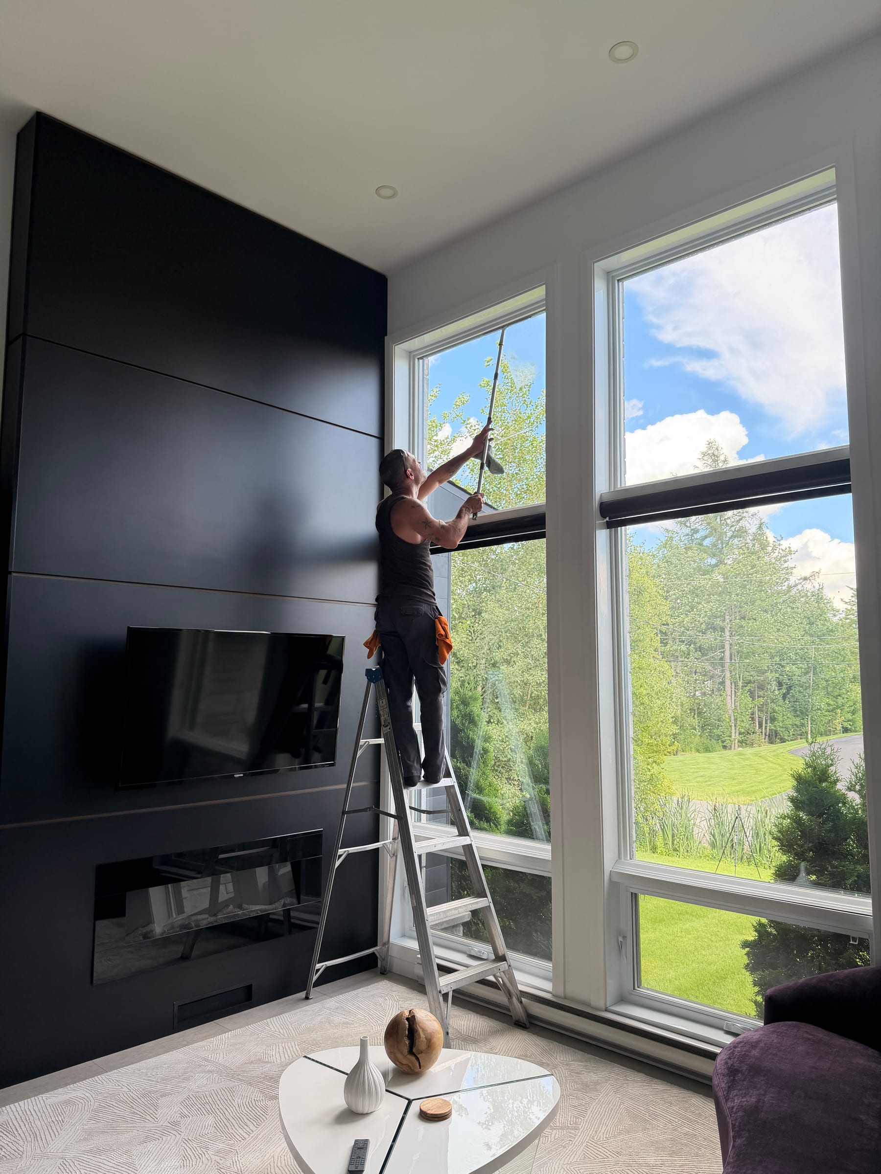 Technicien Bouchneau nettoyant de grandes fenêtres résidentielles à l’intérieur d’une maison